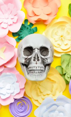 Sarı arka planda el yapımı kağıt çiçekli insan kafatası