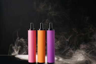 Tek kullanımlık elektronik sigara ve siyah arka planda sigara.