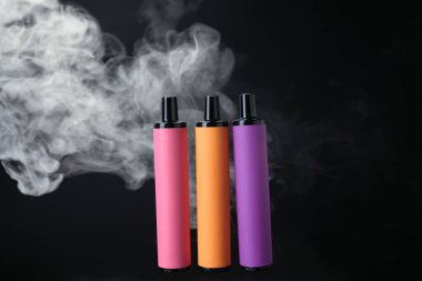 Tek kullanımlık elektronik sigara ve siyah arka planda sigara.