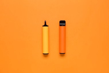 Turuncu arka planda tek kullanımlık elektronik sigaralar.