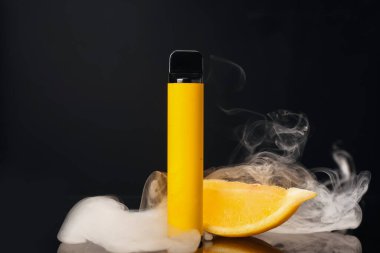 Tek kullanımlık elektronik sigara ve koyu renkli dumanlı limon.