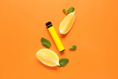 Tek kullanımlık elektronik sigara, nane yaprakları ve turuncu arka planda limon.