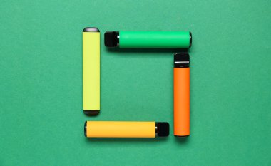 Yeşil arka planda tek kullanımlık elektronik sigaradan yapılmış çerçeve