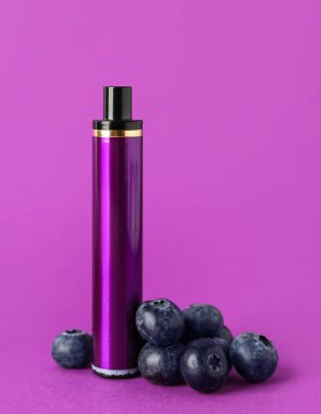 Tek kullanımlık elektronik sigara ve mor arka planda yaban mersini.