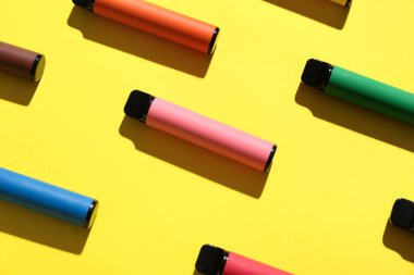 Sarı arka planda tek kullanımlık elektronik sigaralar.