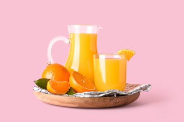 Pembe arka planda bir sürahi taze mandalina suyu.