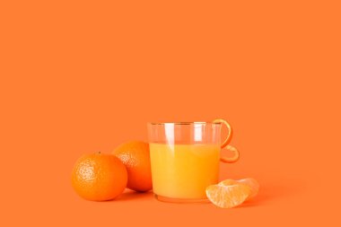 Turuncu arka planda bir bardak taze mandalina suyu