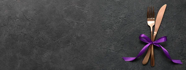 Koyu arkaplanda kurdeleli çatal ve bıçak ile metin için boşluk