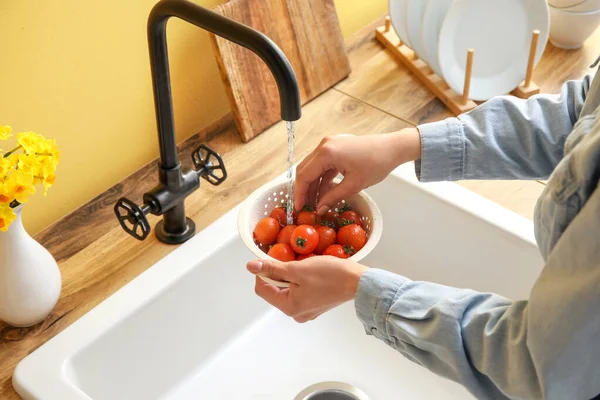 Woman washing fresh tomatoes in kitchen sink, closeup