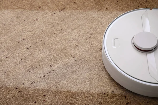 Modern robot süpürgesi yumuşak halıda, yakın plan.