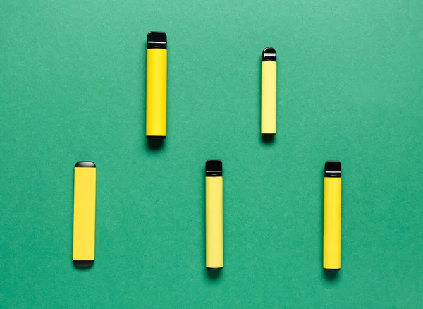 Yeşil arka planda tek kullanımlık elektronik sigaralar.