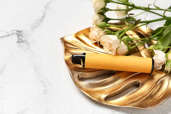 Tek kullanımlık elektronik sigara ve arka planda gül çiçekleri