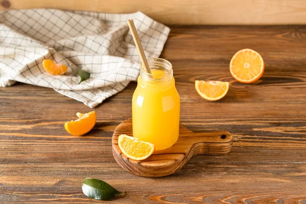 Ahşap arka planda bir şişe taze mandalina suyu.