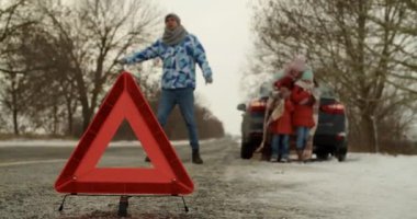 Emergency stop sign and family near broken car on cold winter day
