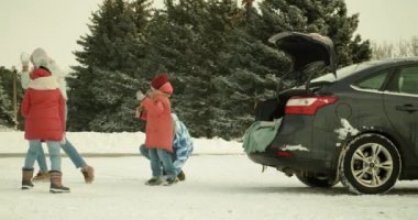 Happy family playing snowballs near car on cold winter day