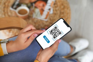 QR kodlu akıllı telefonu evde tutan kadın, yakın plan.