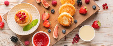 Lezzetli süzme peynirli pankek, beyaz ahşap arka planda böğürtlen ve sos.