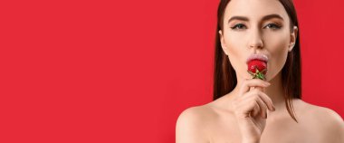 Kırmızı arka planda çilek yiyen seksi genç kadın. Mesaj için yer var.