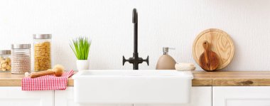 Modern lavabo, farklı aletler ve mutfaktaki beyaz duvarın yakınındaki ürünler. Tasarım için pankart