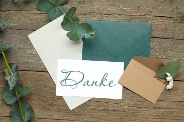 Üzerinde DANKE (Almanca Teşekkür), zarflar ve okaliptüs dalları bulunan bir kart.