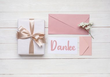 Hediye, Kelime DANKE (Almanca Teşekkür), zarflar ve açık ahşap arka planda güzel çiçekler
