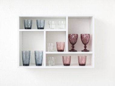 Beyaz duvarda şık gözlükleri olan raf ünitesi.