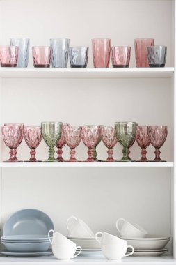 Beyaz raf ünitesinde farklı mutfak aletleri ve boş bardaklar.