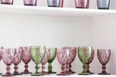 Beyaz raf ünitesinde bir sürü farklı bardak var.