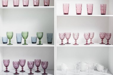 Beyaz raf ünitesinde birçok farklı bardak ve mutfak gereçleri