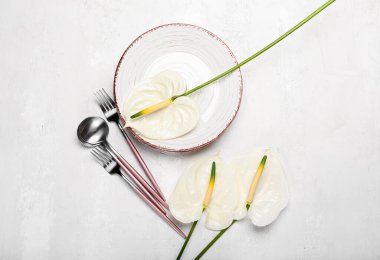 Işık arka planında güzel anthurium çiçekleri ve sofra takımı