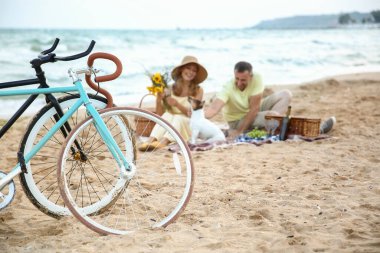 İki bisiklet ve yetişkin çift yaz günü deniz kenarında piknik yapıyorlar.