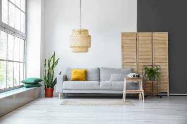 Oturma odasının iç tarafında kanepe ve çiçekli ahşap merdiven.