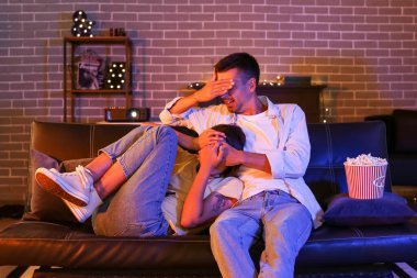 Akşam evde patlamış mısırla film izleyen korkmuş genç bir çift.