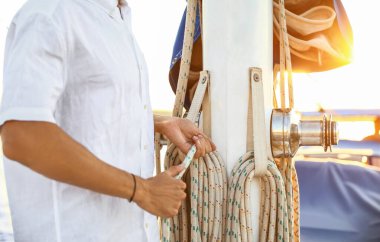 Genç adam yatının donanımını ayarlıyor.