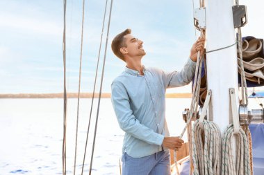 Young man adjusting the rigging of his yacht