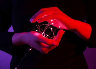 Koyu renkli arka planda parlayan ışıkları olan kadın, yakın plan