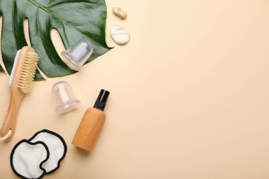 Antiselülit masajı için vakum kavanozları ve bej arka planda palmiye yaprağı olan banyo malzemeleri.