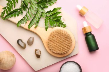 Pembe arka planda gerekli yağ ve masaj fırçası şişeleriyle kompozisyon