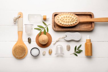 Beyaz ahşap arka planda anti-selülit masajı için vakum kavanozlarıyla değişik banyo malzemeleri.