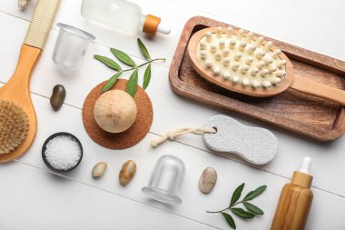 Beyaz ahşap arka planda anti-selülit masajı için vakum kavanozlarıyla değişik banyo malzemeleri.
