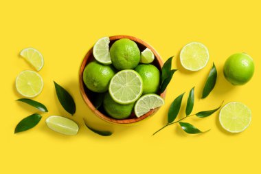 Sarı zemin üzerinde olgun limon ve yapraklar olan kompozisyon