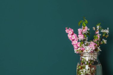 Yeşil duvarın yanında çiçek açan güzel dalları olan cam vazo, yakın plan.