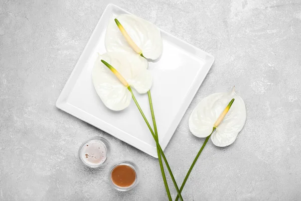 Güzel anthurium çiçekli tabak ve açık arkaplanda bir bardak kahve.