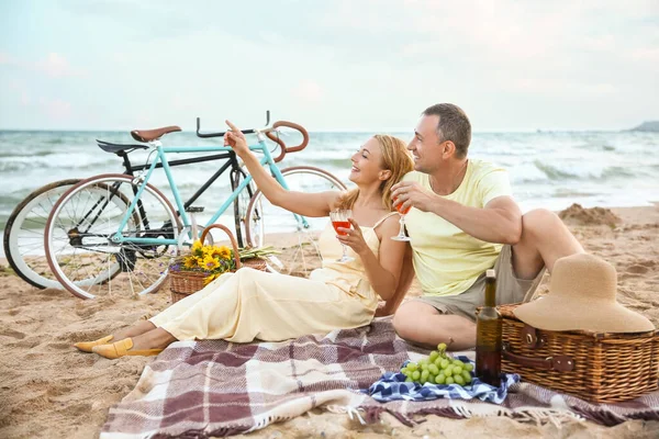 Olgun bir çift yaz günü deniz kenarında piknik yapıyor.