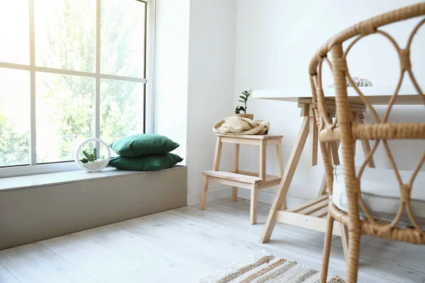 Odanın içinde masa ve hasır sandalyeli tahta merdiven.