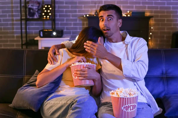 Akşam evde patlamış mısırla film izleyen korkmuş genç bir çift.