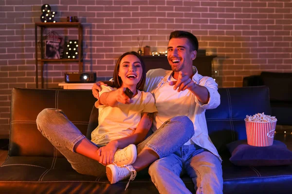 Patlamış mısırlı mutlu genç çift akşam evde film izliyor.