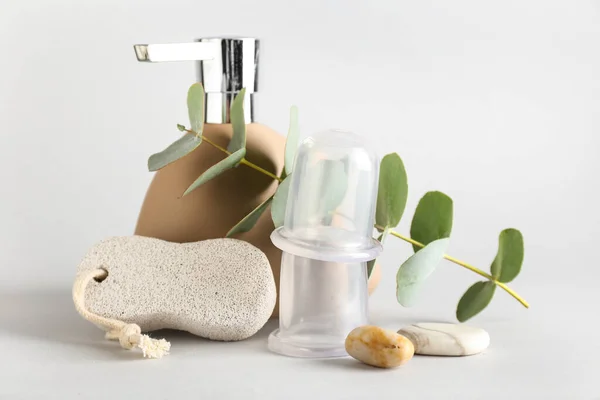 Bottle of cosmetic product, pumice and vacuum jars for anti-cellulite massage on white background