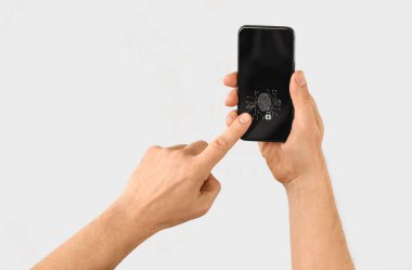 Akıllı telefonlu bir adam parmak izi tarayıcısını kullanarak kişisel hesabına giriş yapar.