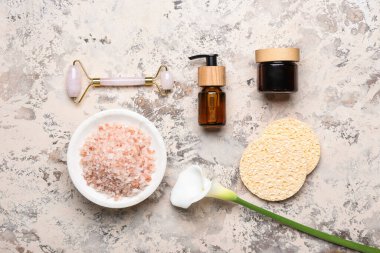 Banyo malzemeleri ve arkaplanda zambak içeren kompozisyon.